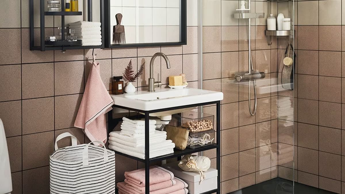 mała różowa łazienka z prysznicem i otwartymi szafkami