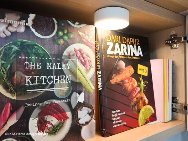 Malay cookbooks displayed in a BESTA shelving unit with swing glass door and KOLVATTEN LED spotlight attached within the shelving unit