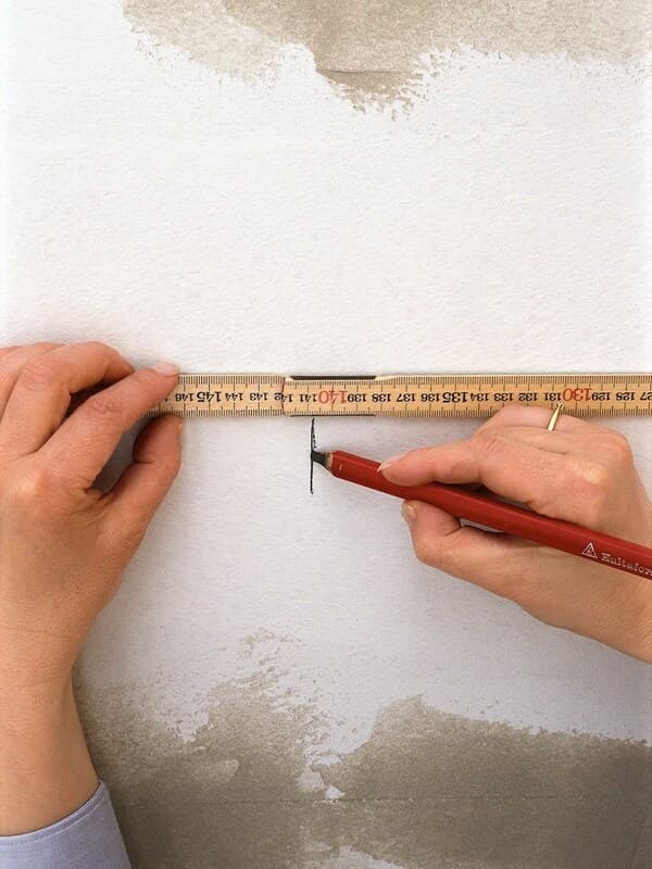 Man die met een potlood een streept zet op de muur.