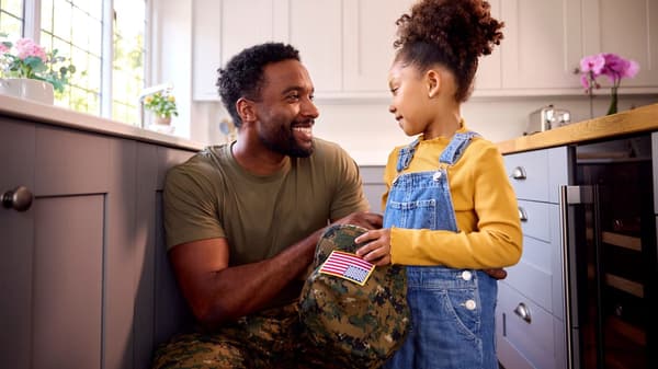 Man in military attire and a child holding the mans military hat