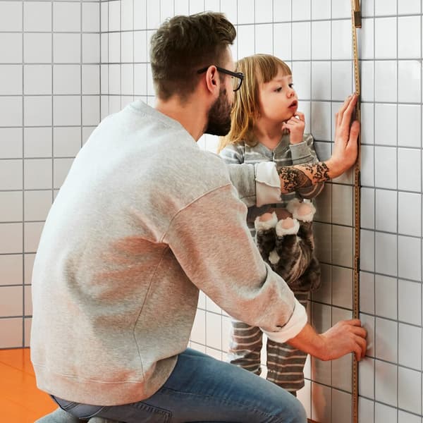 Man measuring a portion of a tiled wall