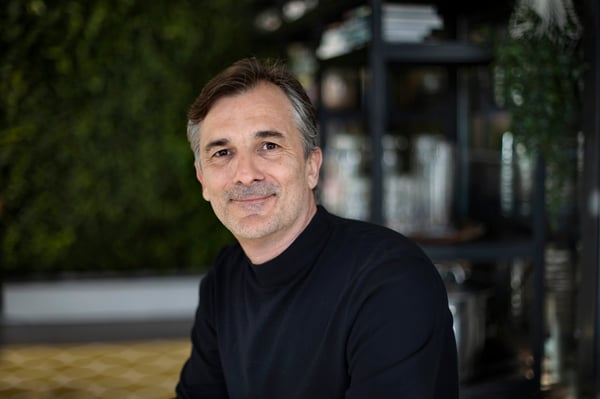 Man med svart polotröja tittar mot kameran