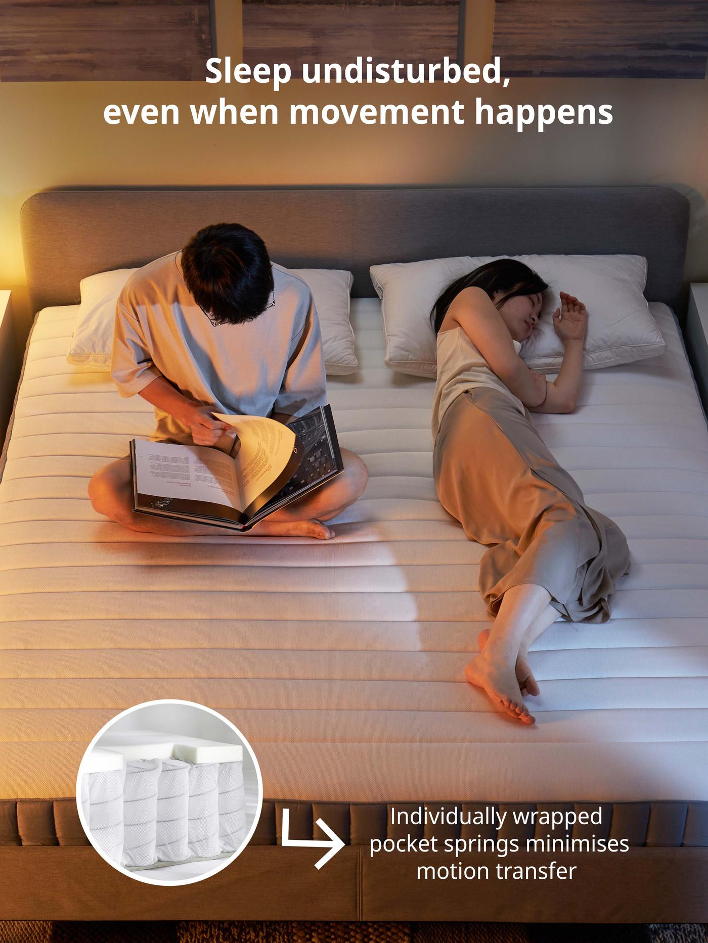 Man reads a book on VALEVÅG pocket sprung mattres while partner sleeps soundly on the other side of the bed. White text reads: Sleep undisturbed, even when movement happens.