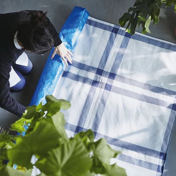 Man rolling up a picnic blanket made from IKEA blue bags