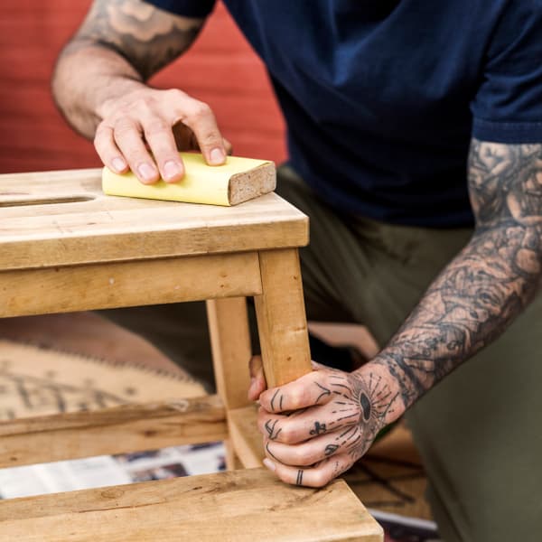 Man sanding a bench