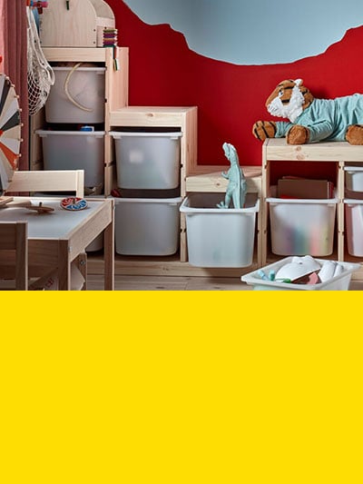 Man sieht ein Kinderzimmer mit verschiedenen Holzmöbeln darunter eine TROFAST Aufbewahrungslösung und darunter einen gelben Balken.