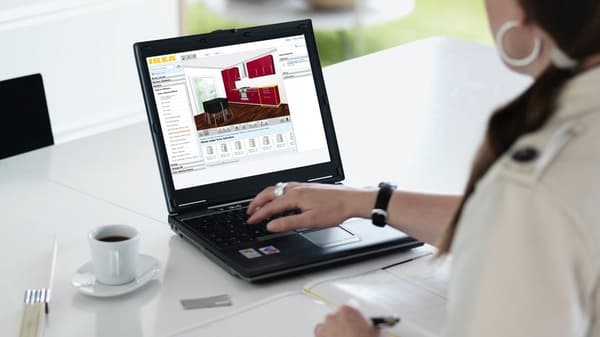 Man sieht eine Frau die eine Hand auf ihrem Laptop hat und eine Küche im IKEA Küchenplaner plant.