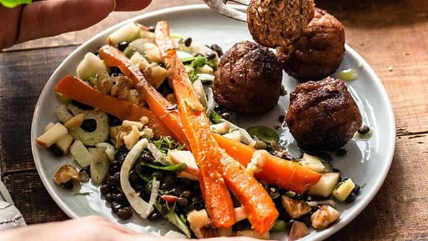Man sieht einen Teller mit Gemüse und veganen Bällchen.