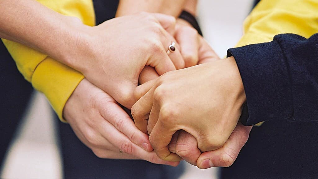 Man sieht mehrere Hände in Nahaufnahme wie sie eine große Gemeinschaft bilden.