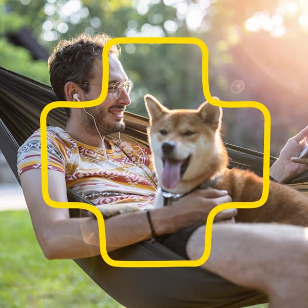 Man sitting in a hammoc with a dog listening e book