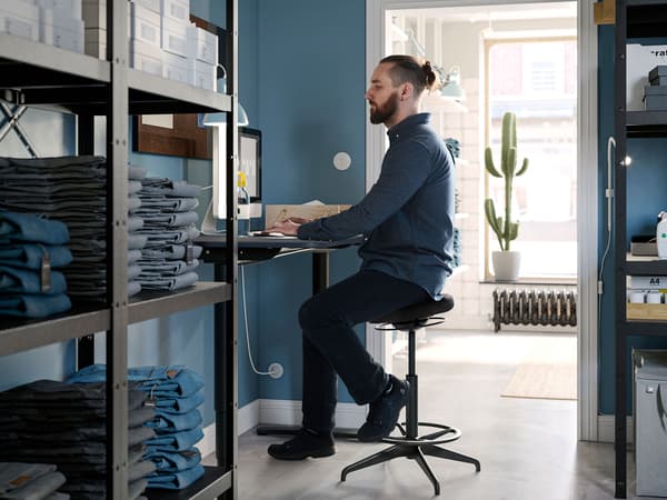 Man som sitter på ett lager vid en dator. 