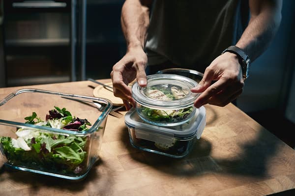 Man using three IKEA 365+ food containers to prepare lunch boxes.