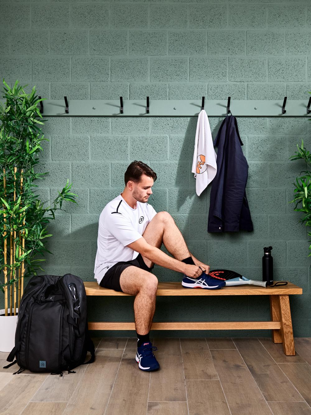 Man zit op een bankje en trekt sportschoenen aan