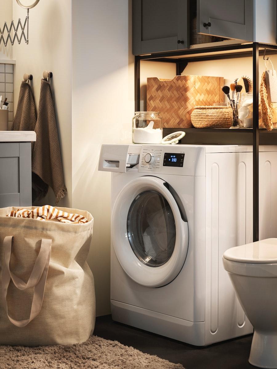 Manchine à laver sous un meuble de rangement, avec un panier à linge à côté