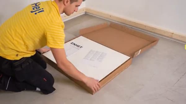 Mand i gul t-shirt er gang med at installere ENHET køkken.