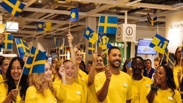 Många IKEA medarbetare som skrattar och viftar den svenska flaggan.