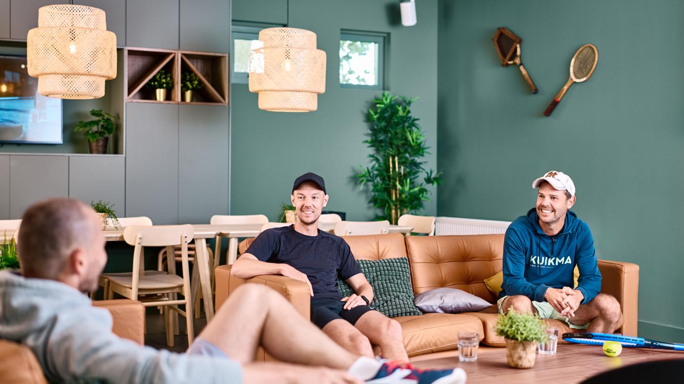 mannen op bruine banken met daarachter houten tafels en stoelen
