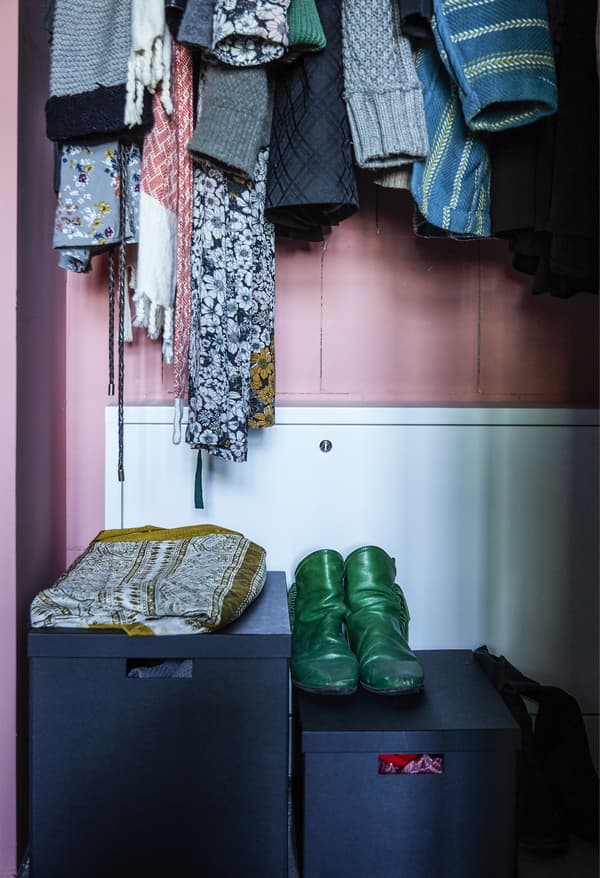 Manteaux accrochés avec boîtes à chaussures en dessous.