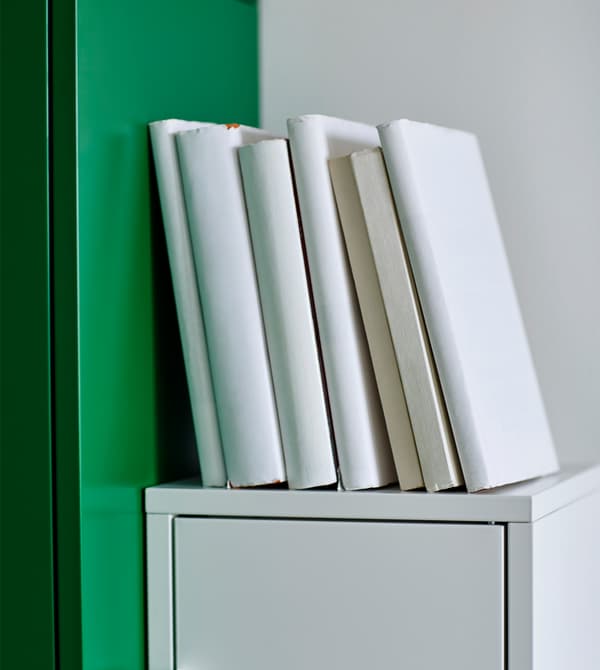 Manuels reliés et couverts de papier blanc posés sur un organiseur de bureau blanc.