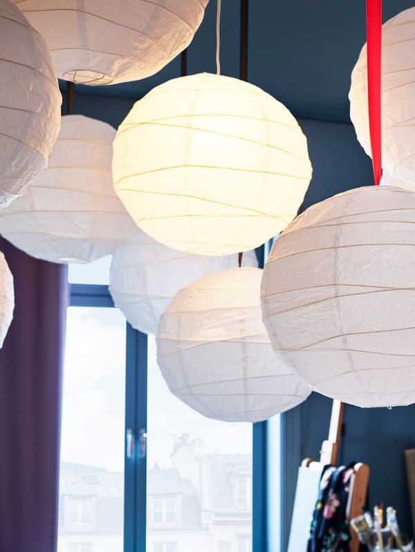 Many white REGOLIT pendant lamp shades made from rice paper.