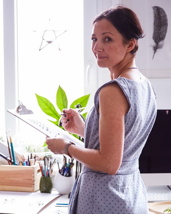Margo artista paper-euskarri bati eusten bere etxeko/logelako bulegoan.