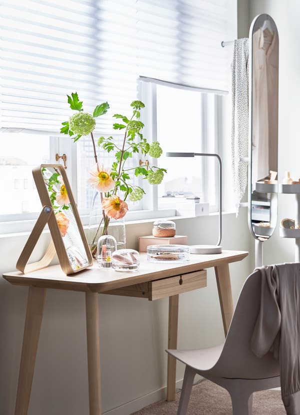 Masa LISABO, din furnir de frasin deschis la culoare, de la IKEA, scaunul din plastic alb-bej ODGER și clopotele din sticlă SAMMANHANG, pentru parfumuri.