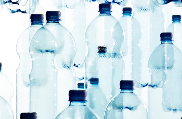 Masse tomme plastflasker i en hvit bakgrun.