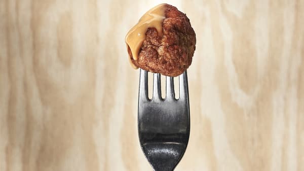 Meat ball with gravy on it tuck on top of a fork