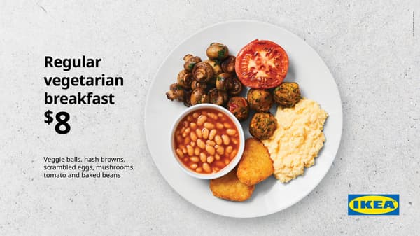 Medium breakfast. White plate on concrete background with scrambled egg, 4 plantballs, fried mushrooms, 1 hash brown, bacon, fried tomato, and small bowl of baked beans