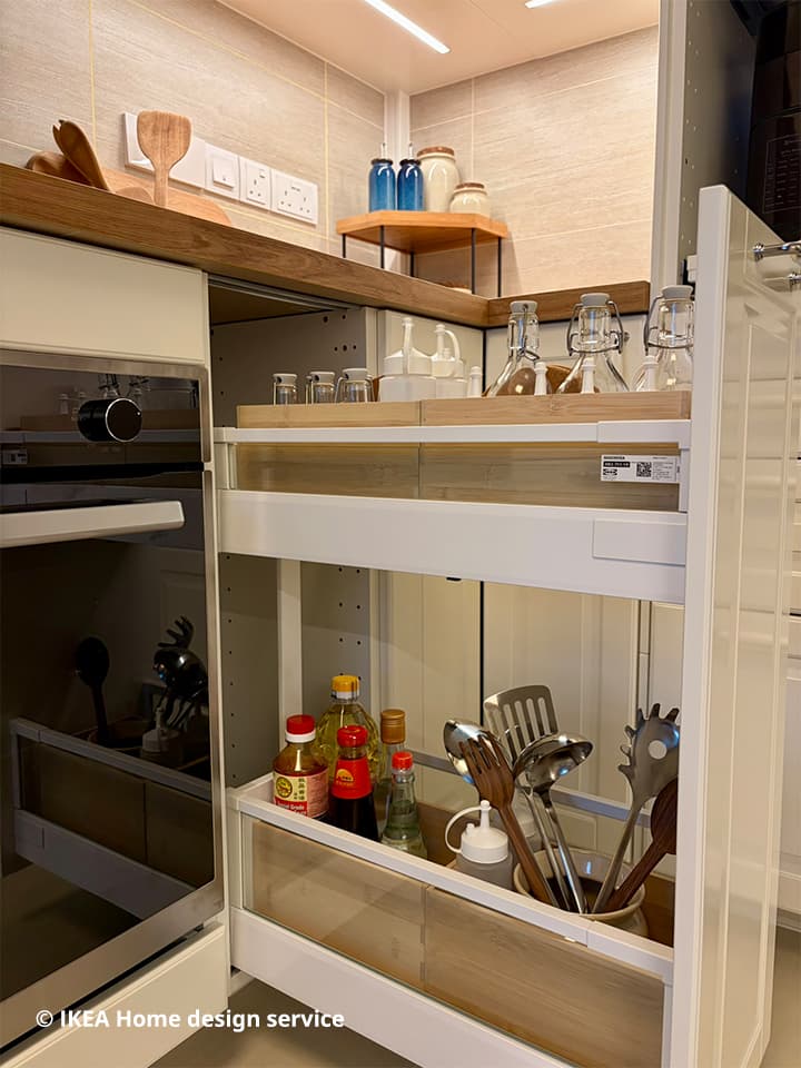 Medium shot of pull-out drawer filled with sauce bottles and kitchen utensils and kitchen accessories in IKEA METOD kitchen drawer.