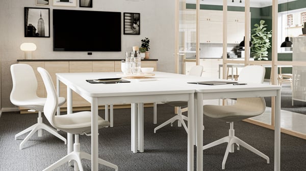 meeting room with white tables, beige chairs, tv in back, lights hanging down, glass window wall