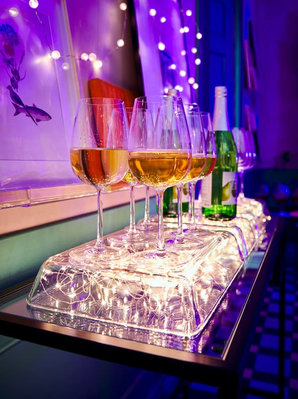 Megfordított MIXTUR üvegedények, alattuk VISSVASS világító füzérrel, ragyogó állvány biztosítva a borospoharak számára.