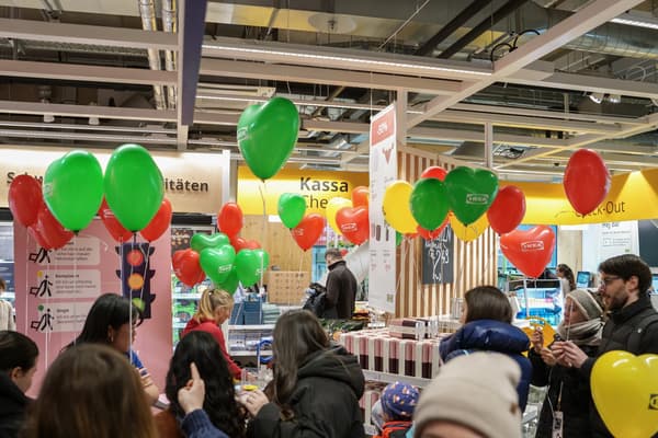 Mehrere Besucher:innen stehen beim Eingang und sind umzingelt von bunte Ballons (rot, grün und gelb)