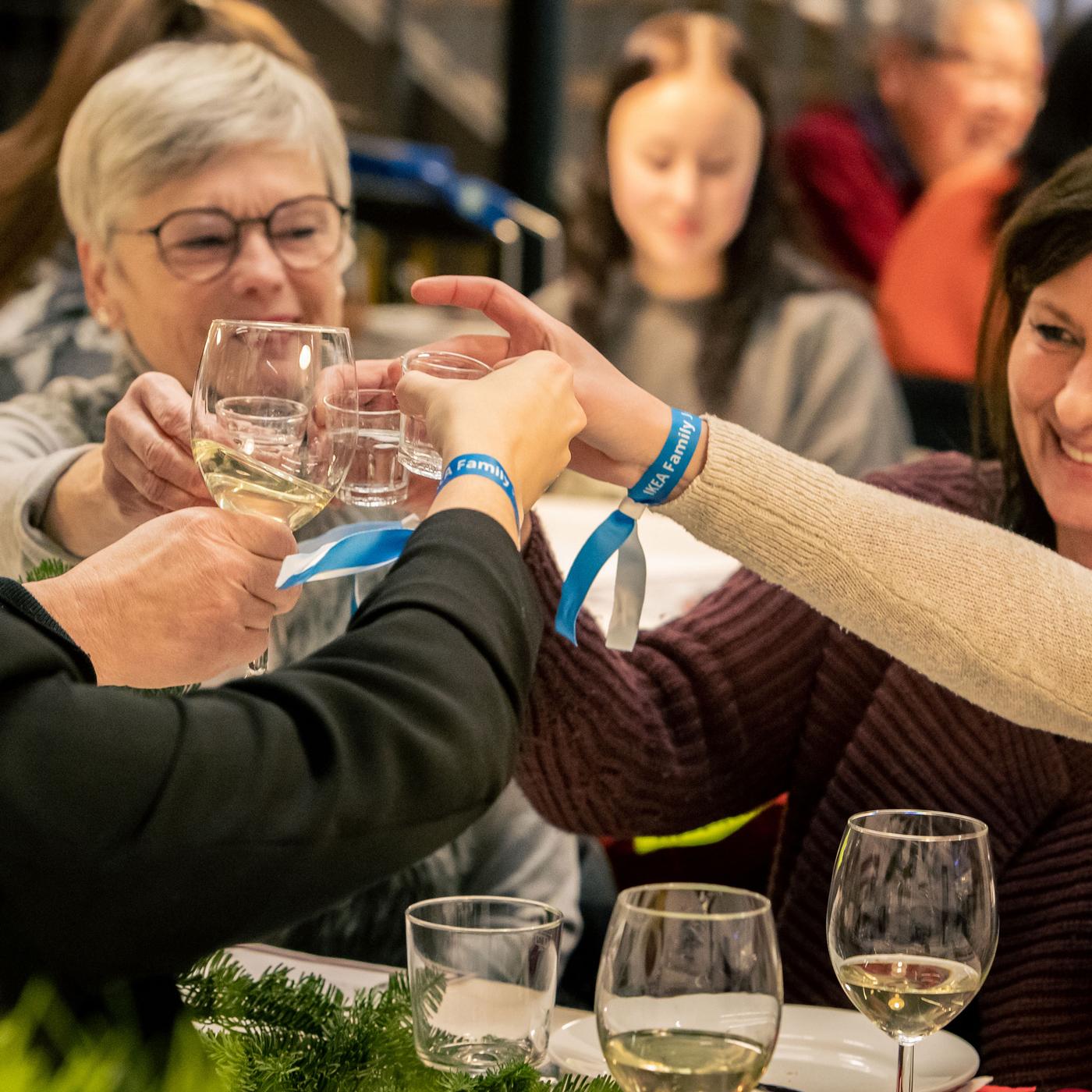 Mehrere Personen sitzen an einem Tisch und stoßen an.