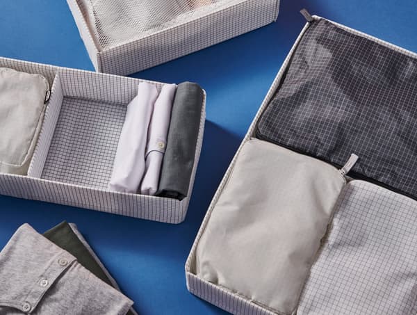 Mehrere RENSARE Taschen stecken in großen STUK Taschen, die auf einer blauen Oberfläche liegen.
