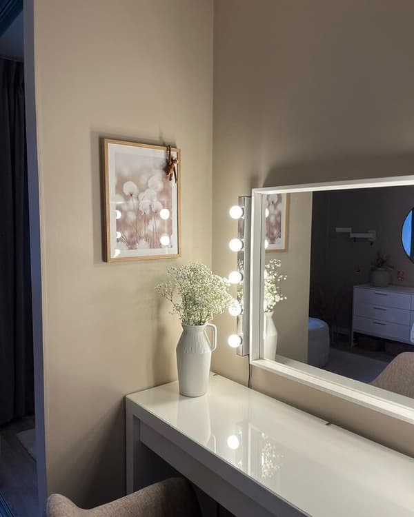 Meikkipöydän eteen kiinnitetty seinäpeili on kehystetty MUSIK-seinävalaisimella.