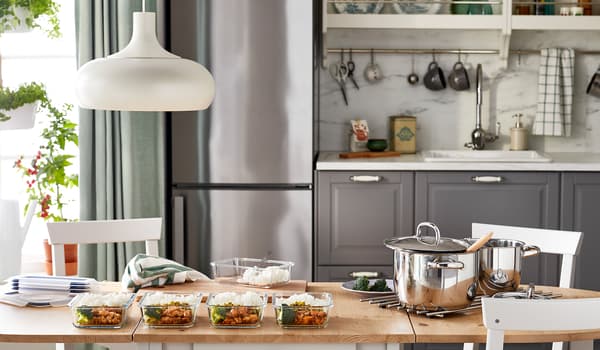 Meja dapur yang di atasnya terdapat hidangan sama yang dimasak secara kelompok dibahagikan daripada periuk besar kepada beberapa bekas makanan kaca yang diletakkan sebaris.