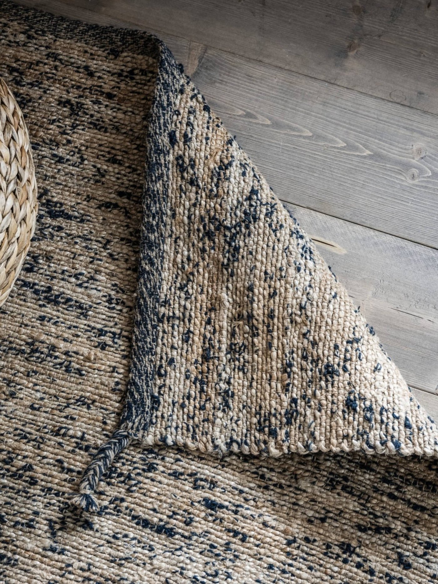 MELHOLT flatwoven rug against wooden floor boards.