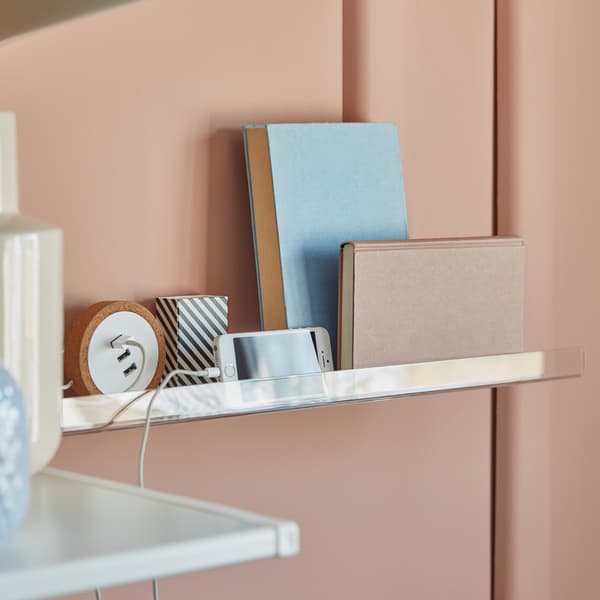 MELLÖSA transparent picture ledge, with books, a mobile telephone being charged and some other smaller home-office items.