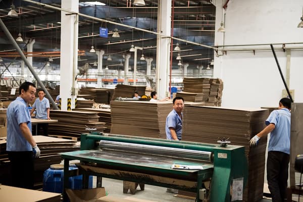 Men working inside an IKEA supplier factory, carefully working with stacks of thin wood surfaces.