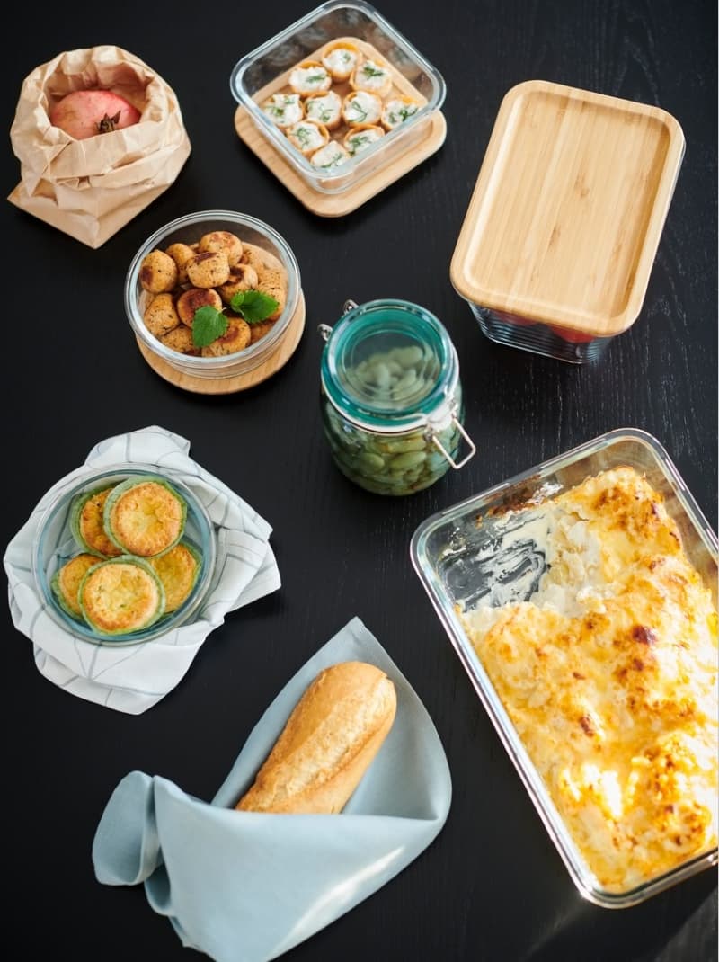 Menjar emmagatzemat en recipients de vidre amb tapa de bambú: gratinat al forn, quiches, galetes, rodanxes farcides, poma embolicada i pot amb cogombres en vinagre.