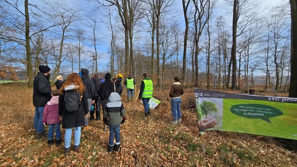 Menschen in einem Bielefelder Waldstück machen sich auf den Weg um Baum-Setzlinge zu pflanzen.