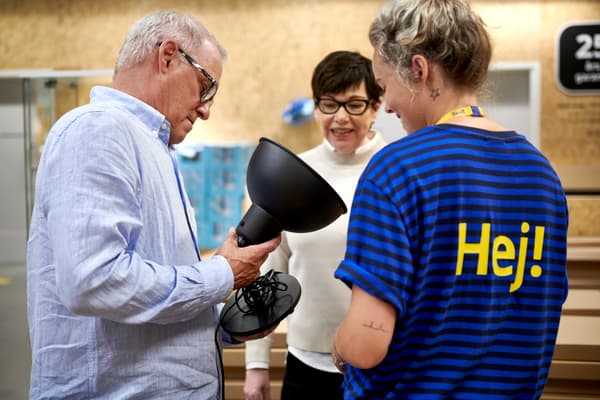 Mensen staan samen met een medewerker van IKEA in de Tweedekanshoek, de man heeft een lamp vast.
