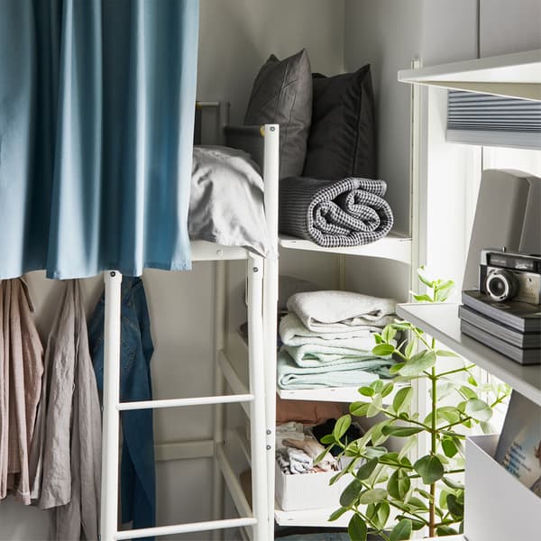 Mensole BOAXEL bianche ai piedi di un letto a soppalco, usate per tenere in ordine lenzuola e altri oggetti – IKEA