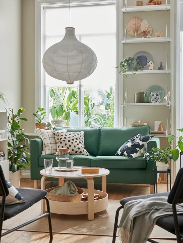 Mesa de centro BORGEBY junto a sofá verde y cojines blancos con diseños en negro.