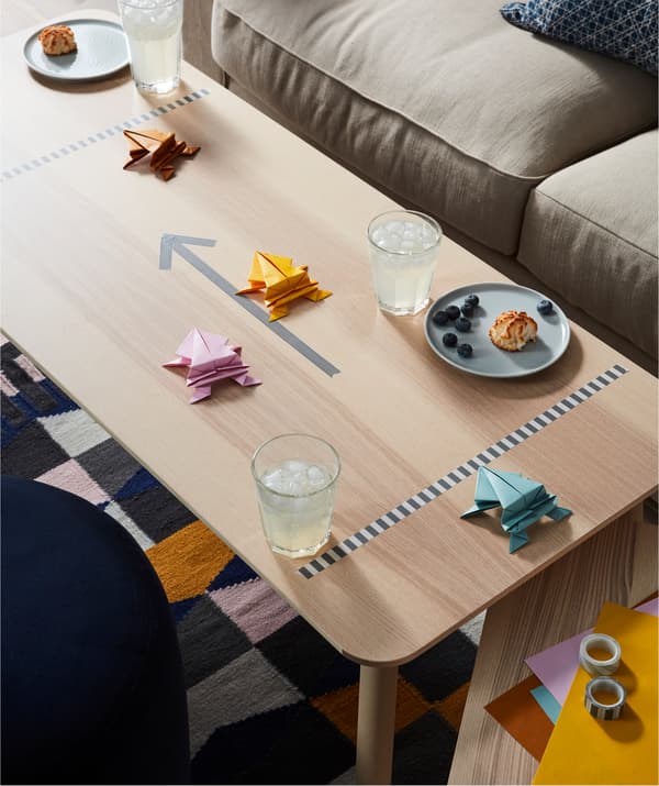 Mesa de centro com pratos e copos – bebidas e petiscos – e uma pista de corridas.