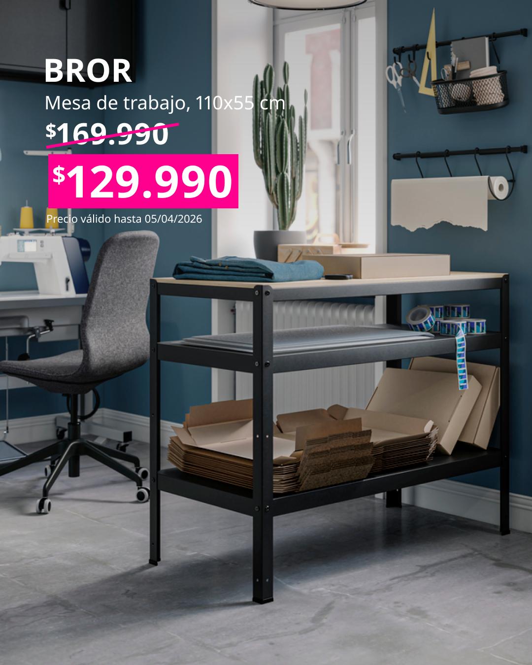 Mesa de trabajo BROR negra en un espacio de oficina en casa, con estantes llenos de cartones y materiales. Texto muestra precio rebajado a $129.990 y medidas 110×55 cm.