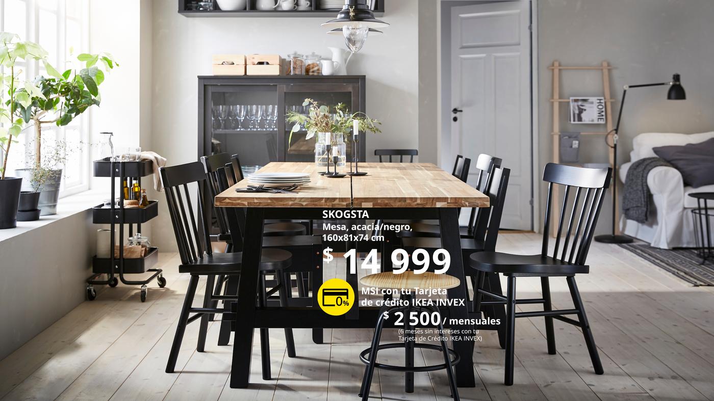 Mesa SKOGSTA de comedor en madera de acacia con patas negras, 160x81x74 cm, diseño robusto y moderno ideal para espacios acogedores con sillas negras y decoración contemporánea.

