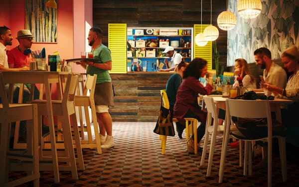 Mesas altas de abedul blancas y taburetes altos de abedul IKEA NORRÅKER en un restaurante pequeño con lámparas de techo de bambú INDUSTRIELL.