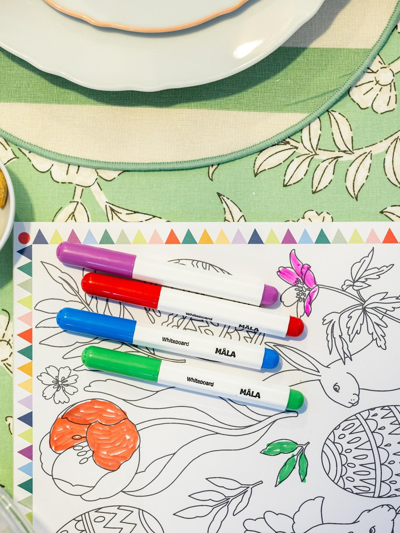 Место за праздничным столом с несколькими тарелками, стоящими друг на друге, сложенной в форме зайчика салфеткой и зелеными украшениями.